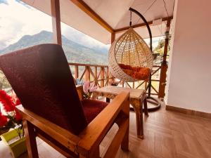 a room with a chair and a hammock on a balcony at Manali Heritage Hotel in Manāli