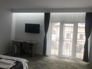 1 dormitorio con escritorio, TV y ventana en Sub Cetate en Rîşnov