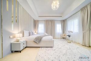 a bedroom with a white bed and a chandelier at Luxury 3BR Villa with Assistant Room at Alvorada 4 Arabian Ranches by Deluxe Holiday Homes in Dubai
