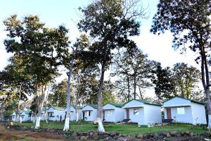 a row of white houses in the woods at The Serene Woods Resort in Matkuli