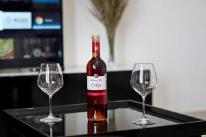 a bottle of wine sitting between two wine glasses at Jimi Apartments 2 in Vlorë