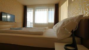 1 dormitorio con 1 cama con ventana y lámpara en Plazs Hotel Siófok, en Siófok