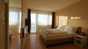 1 dormitorio con 1 cama en una habitación con ventanas en Plazs Hotel Siófok, en Siófok