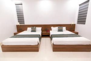 two beds in a room with white walls at Khách sạn Vạn Phúc - Yên Bái in Xóm Soi (2)