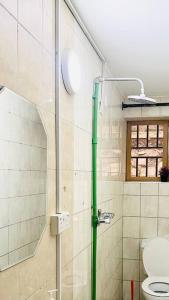 uma casa de banho com um chuveiro, um WC e uma janela. em Cozy Living by Miranda, Acacia - 2 BDR, 4 beds, 3 Bthrms, Unlimited WIFI, Free Parking, Netflix em Kampala