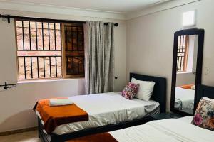 um quarto com 2 camas e uma janela em Cozy Living by Miranda, Acacia - 2 BDR, 4 beds, 3 Bthrms, Unlimited WIFI, Free Parking, Netflix em Kampala
