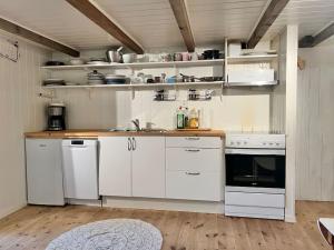a kitchen with white cabinets and white appliances at Lofoten Fjord Apartment - Kvalvika Beach & Ryten in Skjelfjord