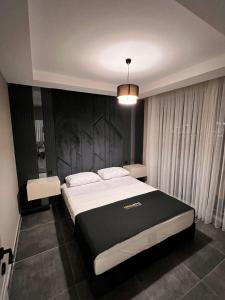a bedroom with a large bed with a black headboard at LİMONOTTO SUİT OTEL in Çiftlikköy