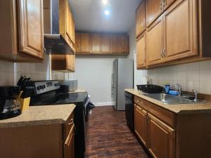 una pequeña cocina con armarios de madera y fregadero en Prime Location 3-Bed Close to NYC, en Jersey City