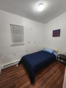 a bedroom with a bed with a blue blanket and a window at Prime Location 3-Bed Close to NYC in Jersey City