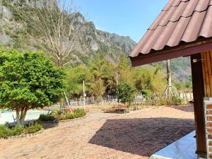 a brick patio with a playground in front of a mountain at Cool Pool Bungalow in Ban Phônmuang