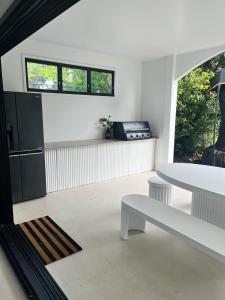 a living room with a white table and a white bench at The_Kennedy_house in Bilinga