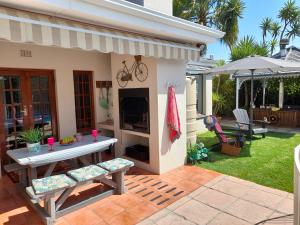 een patio met een tafel en stoelen in een tuin bij Meerendal Cottage-Affordable Luxury,Private Pool in Kaapstad