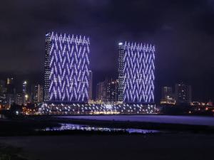 two tall buildings are lit up at night at Penang Amazing SeaView Private Lift 梹城富人区绝美海景公寓私人电梯 in Tanjong Tokong
