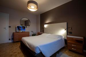 une chambre avec un grand lit blanc et un miroir dans l'établissement 203 Aosta Apartment, à Aoste