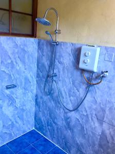 y baño con ducha de azulejos azules y cabezal de ducha. en La Reine Creole, en La Gaulette