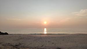 una puesta de sol en una playa con el océano en Beach homestay, en Alleppey
