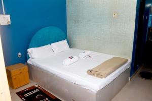a white bed with two towels on it with a blue wall at KonkanParadise,Hotel Malvan Beach in Malvan