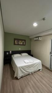 a bedroom with a large white bed in a room at Ônix Inn Hotel Cravinhos in Cravinhos