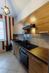 a kitchen with wooden cabinets and a stove top oven at King Piastów & SPA in Szczecin