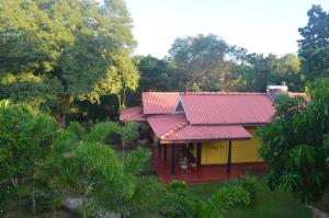 a red and yellow house with a red roof at Amazon Cabanas in Tissamaharama