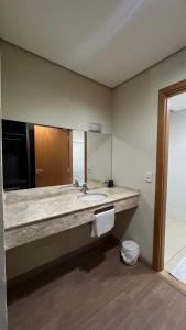 a bathroom with a sink and a large mirror at Ônix Inn Hotel Cravinhos in Cravinhos