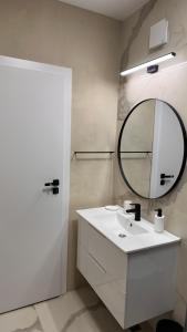 La salle de bains est pourvue d'un lavabo blanc et d'un miroir. dans l'établissement MEB Apartments - Park Lake, à Cluj-Napoca