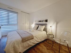 - une chambre blanche avec un lit et une chaise dans l'établissement Appartement 3 salles de bains 3 chambres 6 personnes, à Limoges