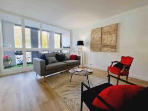 ein Wohnzimmer mit einem Sofa und einem roten Stuhl in der Unterkunft Appartement 3 salles de bains 3 chambres 6 personnes in Limoges