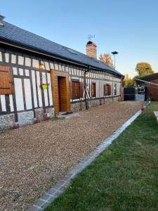 un edificio con techo de gambrel y patio de césped en Belle maison normande avec hamam sauna jacuzi, en Saint-Pierre-de-Cormeilles