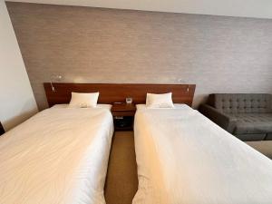 2 camas en una habitación con sofá en Hotel Togariishi, en Chino