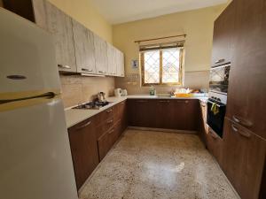 a kitchen with wooden cabinets and a white refrigerator at EEM student Guest House (shared rooms) in Is-Swieqi
