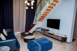 sala de estar con sofá, TV y escaleras en 5 Elizabeth Golf Apartment, en Kigali