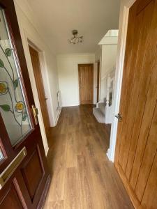 an empty room with a wooden door and a hallway at Lovely modern, well-kept house in Sidcup