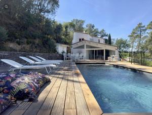 a swimming pool with chairs and a house at Ormarine in Fréjus