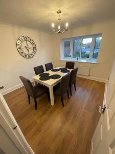 a dining room with a table and chairs and a clock at Lovely modern, well-kept house in Sidcup