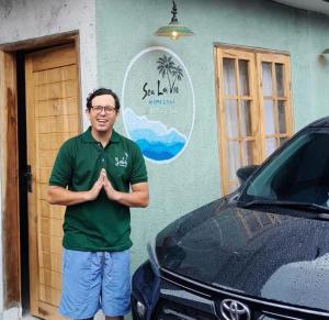 a man in a green shirt standing in front of a car at Sea La Vie in Pangandaran