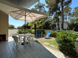 eine Terrasse mit einem Tisch, Stühlen und einem Sonnenschirm in der Unterkunft Residenza Venus in Castiglioncello