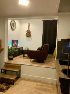 蒙特勒伊的住宿－L'Industriel : Duplex Montreuil，客厅配有椅子和墙上的吉他
