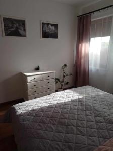 a bedroom with a bed and a dresser and a window at Apartament Herberta in Oborniki Śląskie