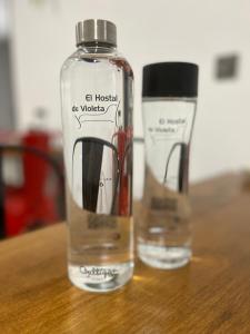 two bottles of water sitting on a wooden table at El Hostal de Violeta in Tomelloso