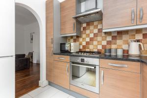 La cuisine est équipée de placards en bois et d'un four avec plaques de cuisson. dans l'établissement The Chiswick Apartments, à Londres