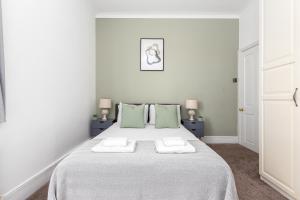 a white bedroom with a large bed with green pillows at The Chiswick Apartments in London
