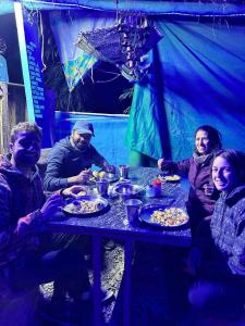 eine Gruppe von Menschen, die an einem Tisch mit Essen sitzen in der Unterkunft Veera's Hostel in Pushkar