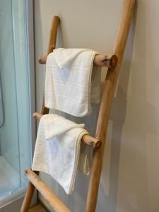 een houten handdoekenrek met 2 handdoeken erop bij La petite halte in Godshuis