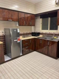 a kitchen with wooden cabinets and a stainless steel refrigerator at شقة غرفتين وصالة مدخل خاص باركنج سيارة in Riyadh Al Khabra
