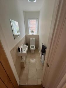 een badkamer met een toilet, een wastafel en een raam bij Lovely modern, well-kept house in Sidcup