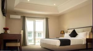 1 dormitorio con cama, escritorio y ventana en TIME Royal Ambassador Hotel en Harbel