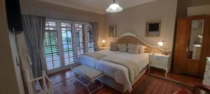 a bedroom with a large bed and a large window at Meerendal Cottage-Affordable Luxury,Private Pool in Cape Town