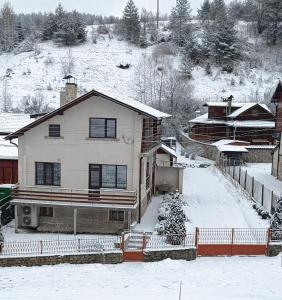 a house is covered in snow in a town at Самостоятелна къща за гости Рилски кът Маджаре in Madzhare